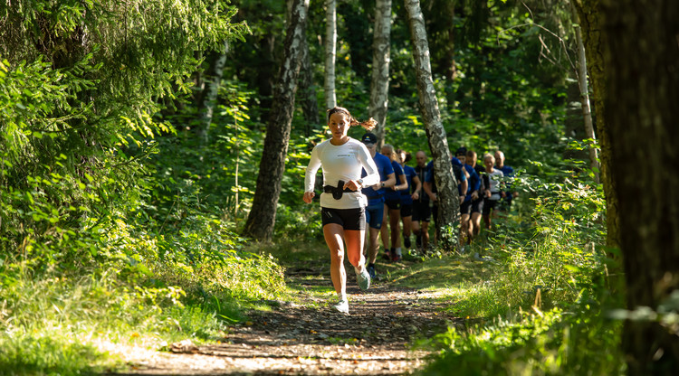 Charlotta Kalla i täten med flera andra personer springer längst en stig i skogen.