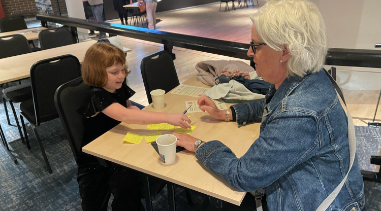 En flicka och hennes mormor sitter vid ett bord och skriver på post-it-lappar