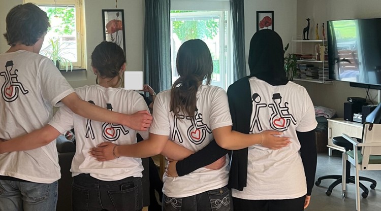 Fyra ungdomar står och håller varandra med gemensamma t-shirts för ung omsorg.