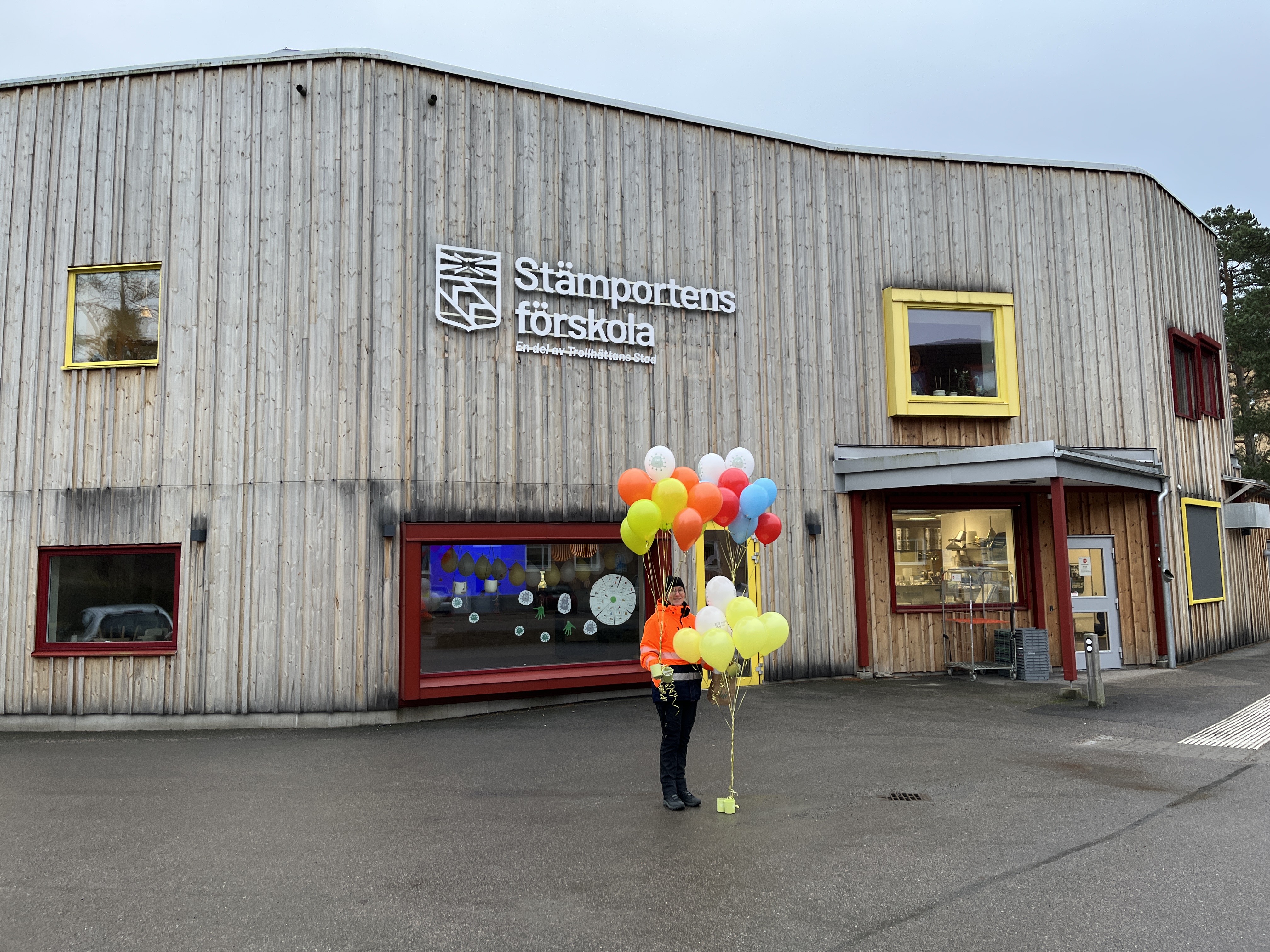 Medarbetare som står utanför Stämportens förskola och håller i flera färgglada ballongbuketter. 