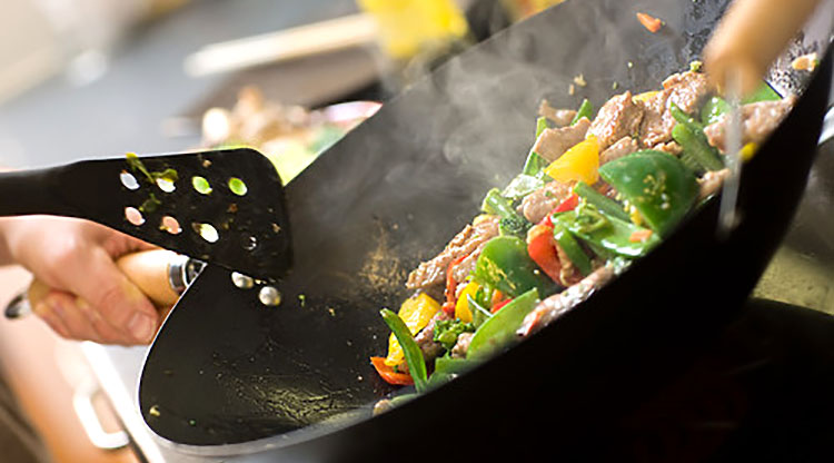 Bild på wokpanna med kött och grönt i som steks.
