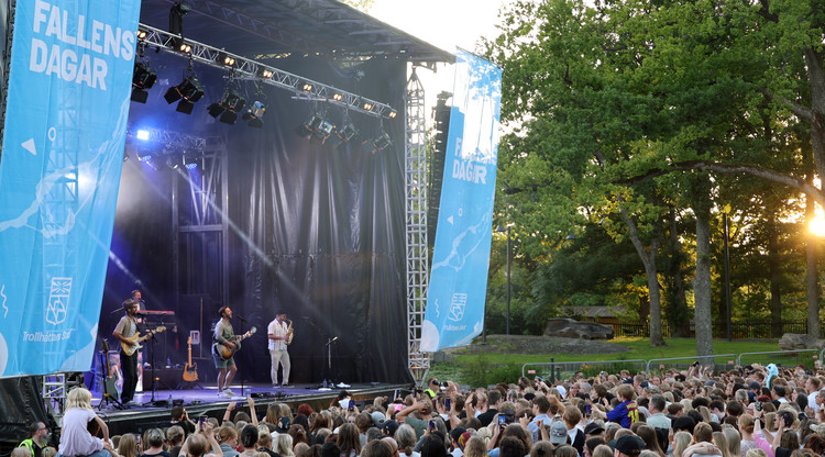 Måns Zelmerlöw med band på scen inför publik i park.