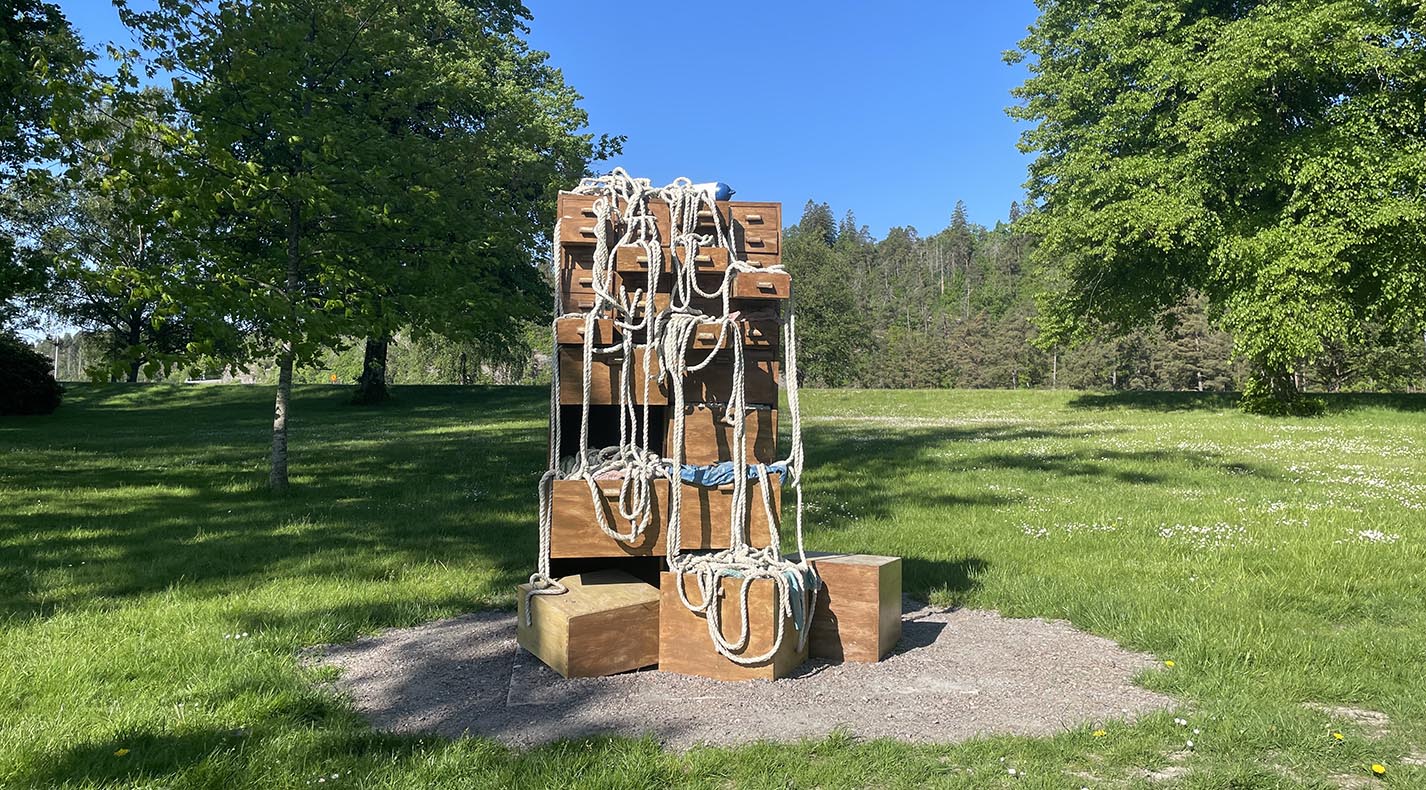 Bronsskulptur föreställande arkivskåp med öppna lådor, rep och fendrar hänger från skåpet